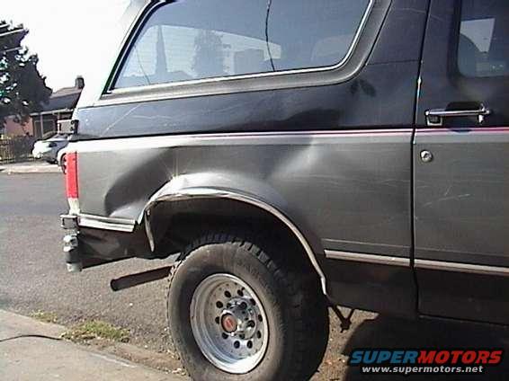 Dark gray Ford Bronco with significant rear quarter panel damage, seen from the side