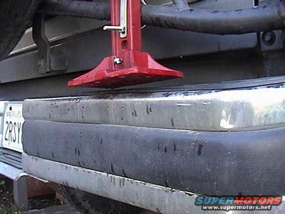 Red hi-lift jack on a 1990 Ford Bronco rear bumper. License plate visible