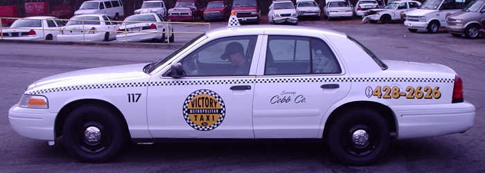 1996 Ford Crown Victoria taxi cab with checkered stripe and "Victory Taxi" logo