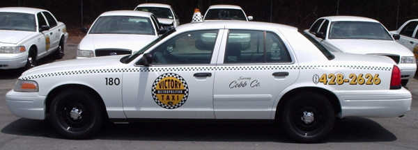 White taxi cab with "Victory Taxi" logo and phone number 0428-2626 on the side. Other white cabs are parked nearby