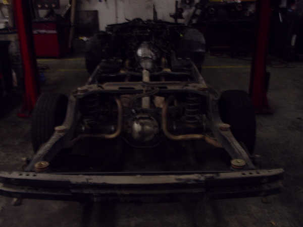 Car chassis with suspension and exhaust visible, viewed from the front