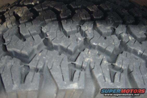 Close-up of tire tread with "SUPERMOTORS" logo visible