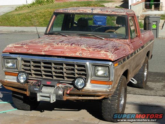Brown and red Ford Bronco with peeling paint, winch, and aftermarket bumper