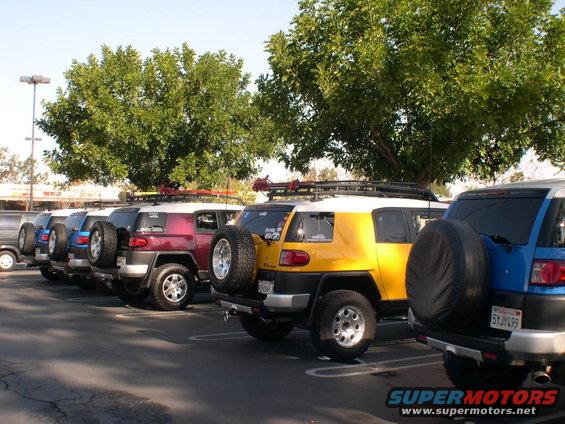Several Toyota FJ Cruisers parked in a lot, yellow, red, and blue models visible