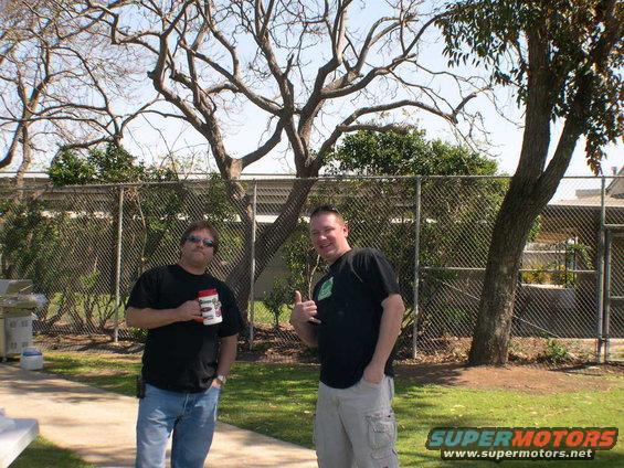 Two men in a backyard, one holding a mug