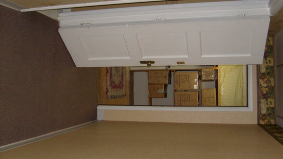 Room interior with a closed white door, boxes stacked behind it, and patterned wallpaper