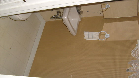 Bathroom sink with chrome pipes, toilet, and towel rack with a folded towel