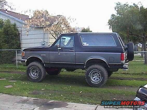 Ford Bronco parked on grass, side view. Has a spare tire on the back