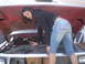 1979 Ford F-150 - A woman works on the engine of a vehicle with its hood open.