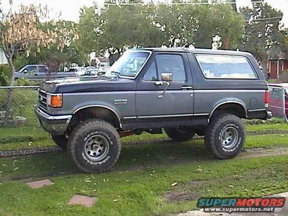 1990 Ford Bronco lifted with large tires, parked on grass