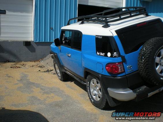 Blue and white 2007 Toyota FJ Cruiser, rear view, with roof rack and spare tire. Sticker on rear window says 'Got Dirt?'