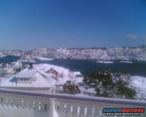 snow-covered houses and coastline under a clear blue sky
