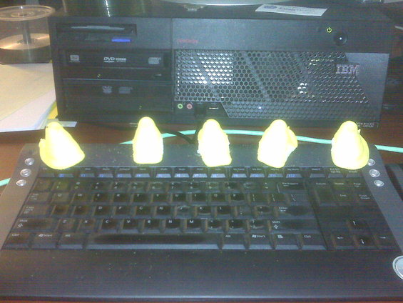 Yellow marshmallow candies arranged on a keyboard before an IBM computer
