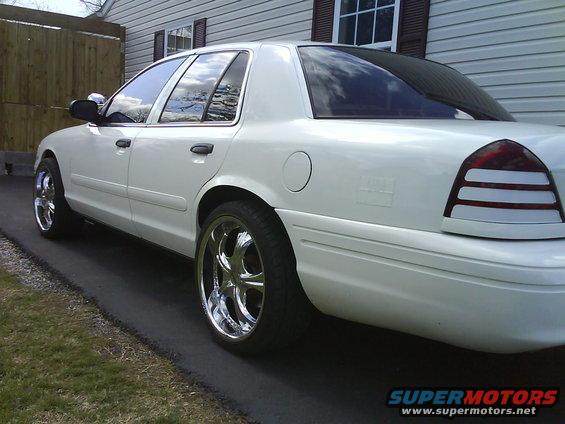 White 2003 Ford Crown Victoria with chrome rims parked on asphalt driveway