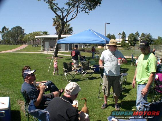 People gathered for a picnic in a park with a blue canopy