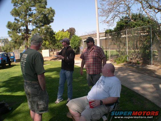 Four guys talking outside near a blue SUV