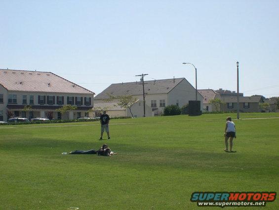 People on a grassy field with buildings in the background