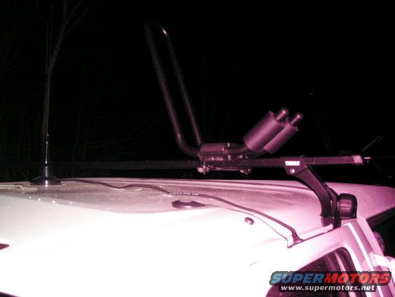 White vehicle roof with a roof rack holding two exhaust pipes and an antenna