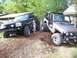2004 Jeep TJ - Two modified Jeeps, a silver Wrangler and a black Grand Cherokee, are parked side-by-side on a patch of mulch.