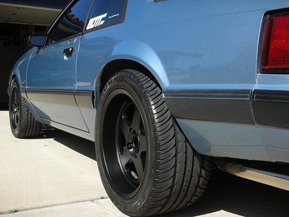 Blue car with black wheels and aftermarket decals on the rear quarter window