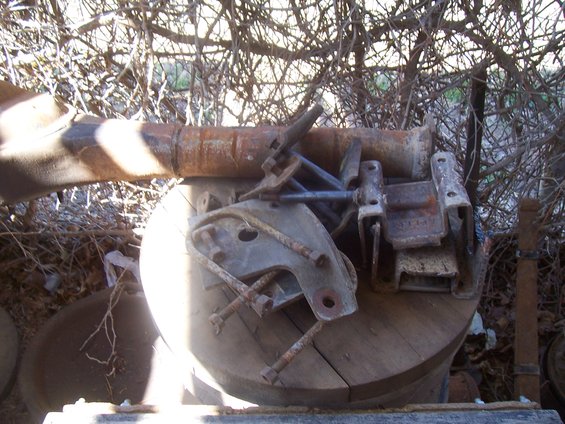 Pile of rusty metal parts including a jack and bolts on a wooden spool