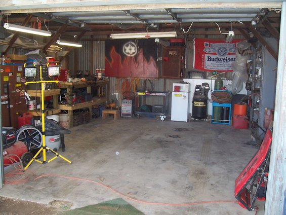 Garage interior with workbenches, tools, air compressor, and Budweiser flag