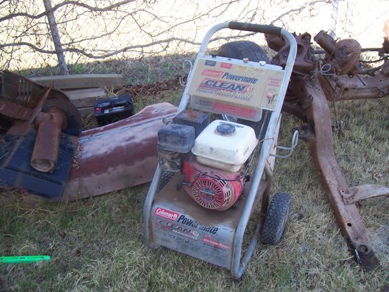 Pressure washer and rusted vehicle frame on grass