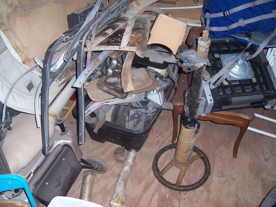 Pile of assorted car parts including trim pieces, interior components, and a steering column with a wheel