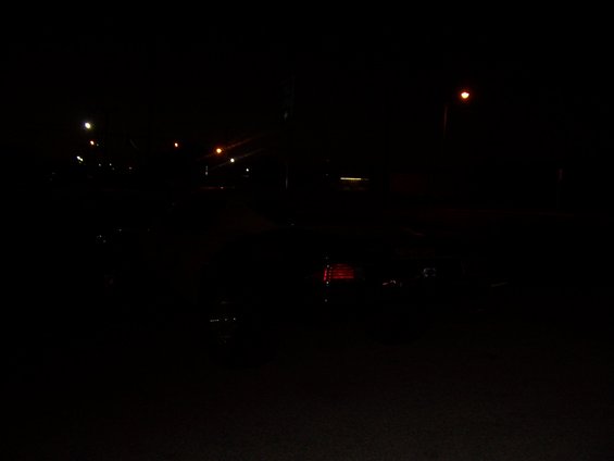 dark street scene at night with streetlights and reflections on wet pavement