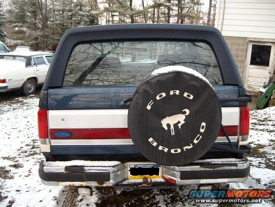 1988 Ford Bronco rear view with spare tire cover and Pennsylvania license plate. White car visible to the left