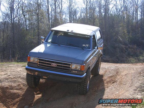 Gray 1989 Ford Bronco 4x4 driving on a dirt trail