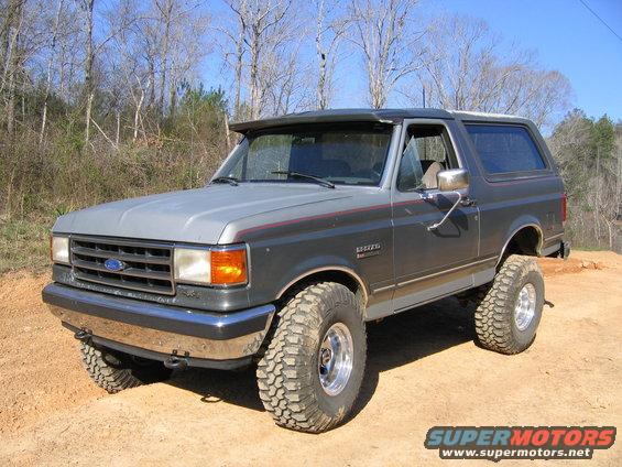 Gray 1989 Ford Bronco with off-road tires parked on dirt
