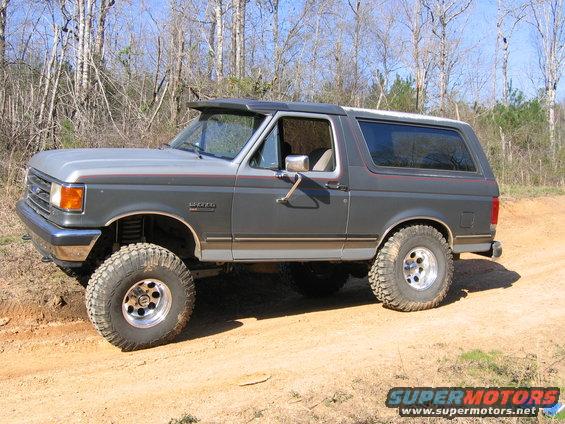 Gray Ford Bronco with lifted suspension and large tires on a dirt road
