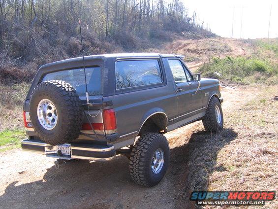 1989 Ford Bronco with spare tire on rear, driving on dirt trail