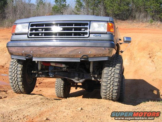 Gray Ford Bronco with lifted suspension and large tires on a dirt track