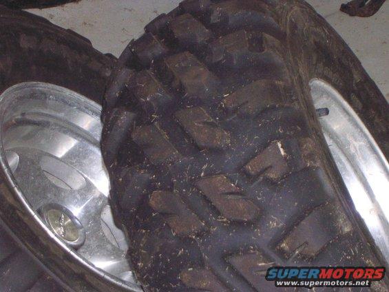 Two ATV tires with silver alloy rims, one tire in focus showing aggressive tread pattern