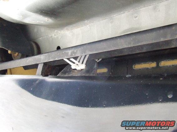 Underbody of a vehicle with black bumper and white zip ties securing a black bar