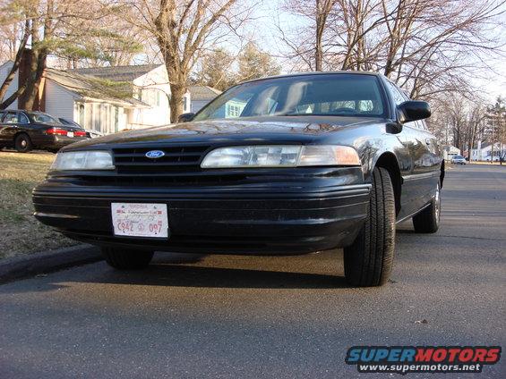 Black Ford Crown Victoria parked on a street. Another black car is parked in the background