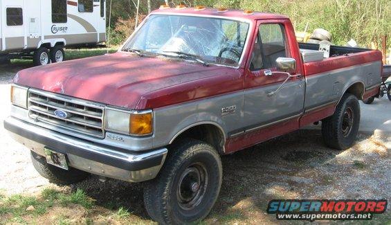 1989 Ford F-250 pickup truck, red and gray two-tone paint, cracked windshield, parked outdoors