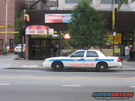 1999 Ford Crown Victoria police car, side view, parked in front of Dunkin' Donuts