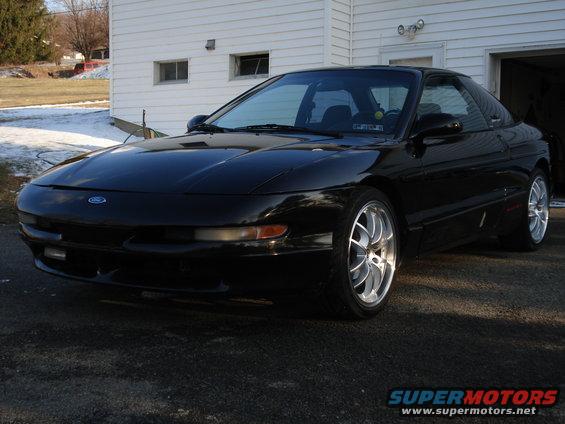 Black 1993 Ford Probe parked in front of a white garage