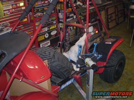 Red dune buggy with a roll cage, sitting in a garage with tool chests in the background. The word 'ODYSSEY' is visible on the frame