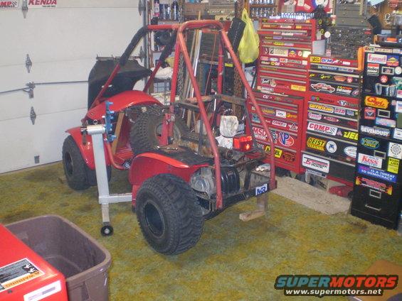 Red off-road vehicle on a stand in a garage with tool chests