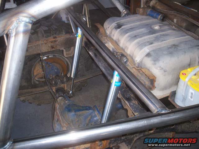 Roll cage tubing over rear axle, fuel tank, and a yellow battery