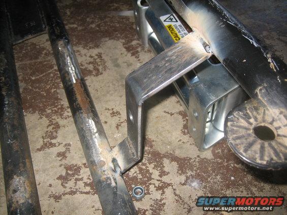 metal brackets welded to pipes, with a caution sticker visible