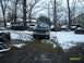 1988 Ford Bronco - A dark pickup truck is parked in a snowy yard with other vehicles and equipment.
