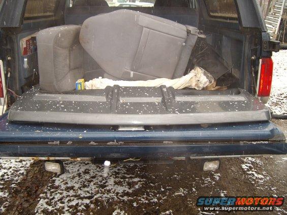 Blue Ford Bronco rear bumper with seats and parts in the bed