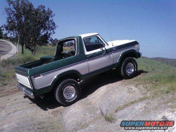 Two-tone green and white 1978 Ford Bronco on a dirt hill, front-right tire elevated
