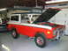 1992 Ford Mustang - This two-tone Ford Bronco is parked inside a garage with its hood up, revealing the engine compartment.