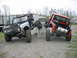 1992 Ford Mustang - Two heavily modified SUVs are positioned on a ramp system in an outdoor lot.